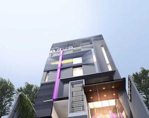 Un hotel moderno con un diseño arquitectónico único, que destaca por una llamativa franja vertical y una combinación de materiales de vidrio y metal.