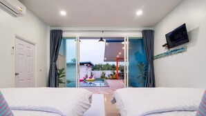 A hotel room with two beds, a TV, and a view of an outdoor pool area. - Baan Farm Sook (Cha-am)