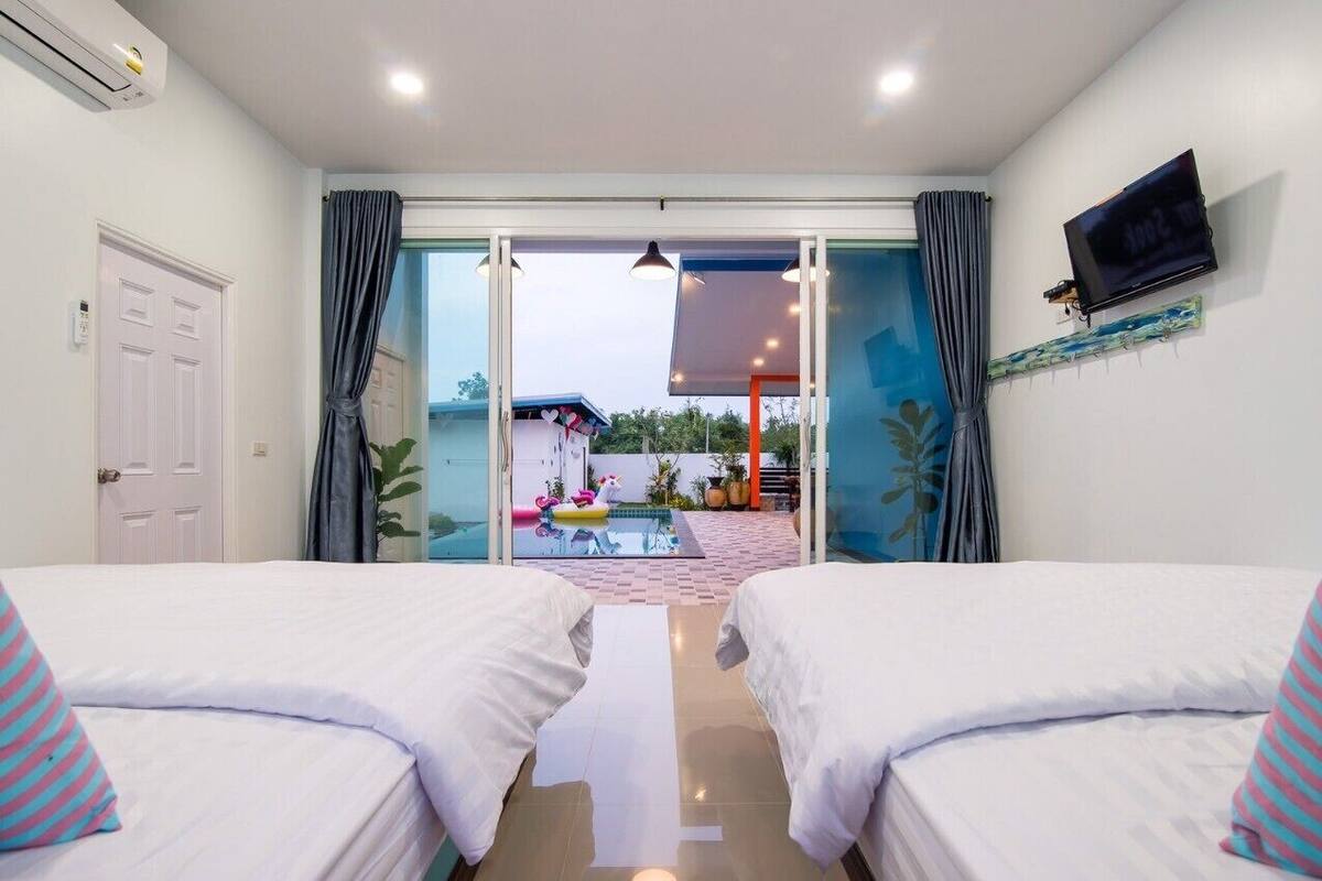 Een hotelkamer met twee bedden, een televisie en uitzicht op een buitenzwembad.