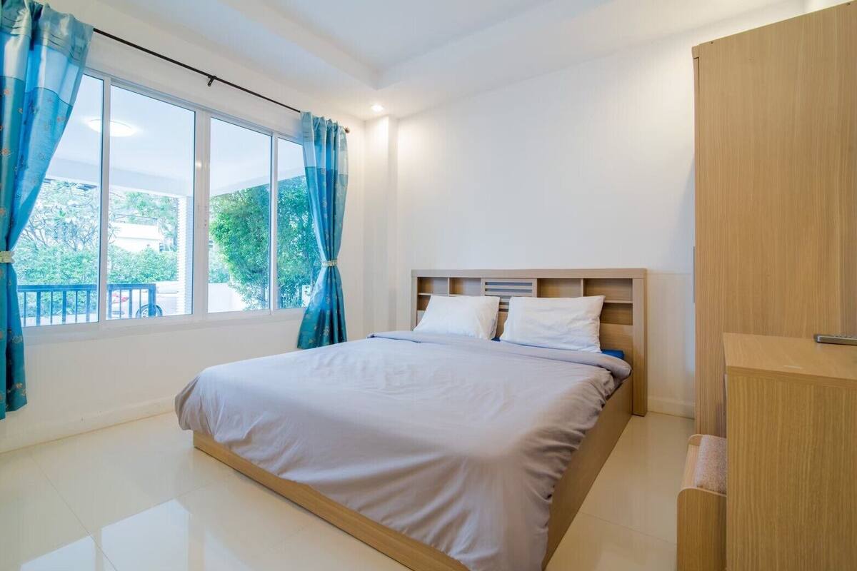 Een slaapkamer met een bed, een houten garderobe en een raam met gordijnen.