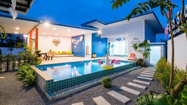 A modern house with a swimming pool, a dining area, and a living room with a sofa and a TV. - Baan Farm Sook (Cha-am)