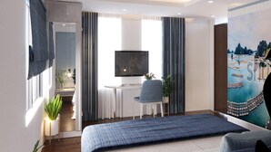 Een moderne hotelkamer met een groot bed, een bureau met een televisie, een stoel en een schilderij aan de muur.