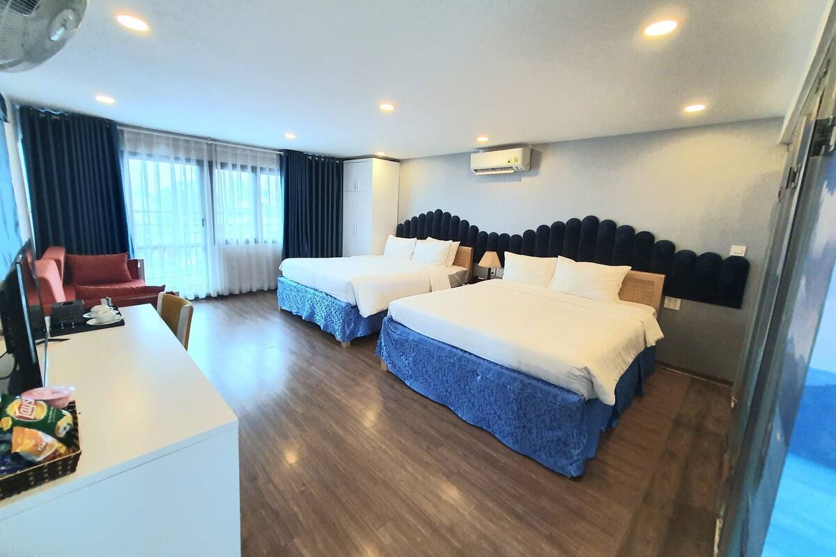 Une chambre d’hôtel avec deux lits, un bureau, une chaise, une télévision et une fenêtre avec des rideaux.