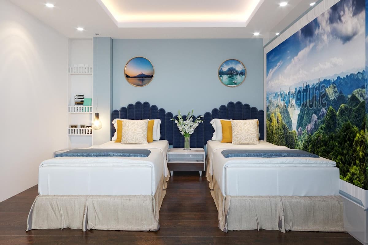 Une chambre d’hôtel moderne avec deux lits, une grande fresque murale et une vue sur un paysage montagneux.