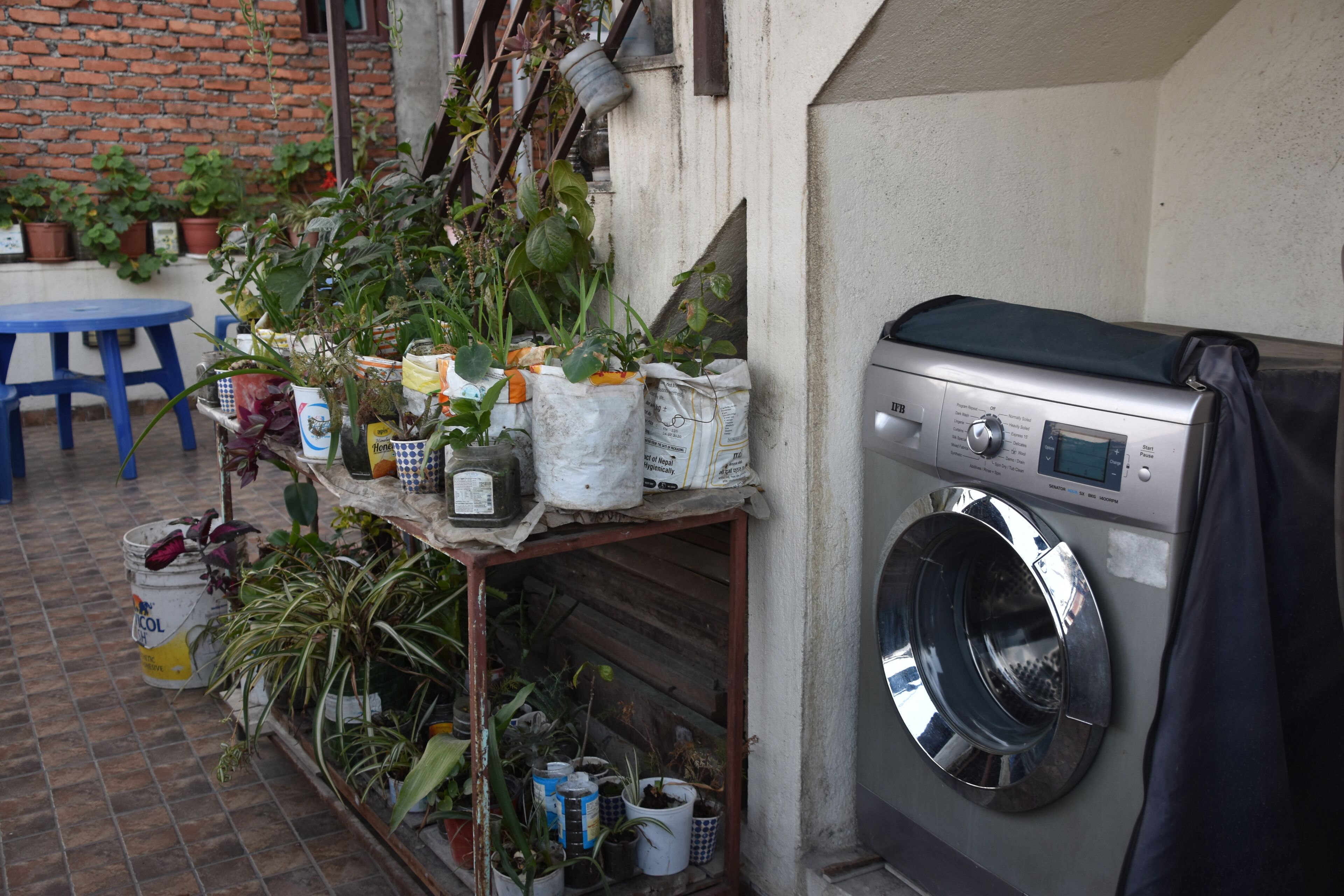 Un espace buanderie comprenant un lave-linge, une table et diverses plantes en pot.