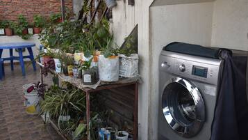 Un espace buanderie comprenant un lave-linge, une table et diverses plantes en pot.