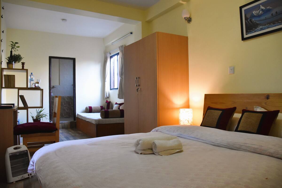 A hotel room with a bed, a wardrobe, a desk, and a chair.