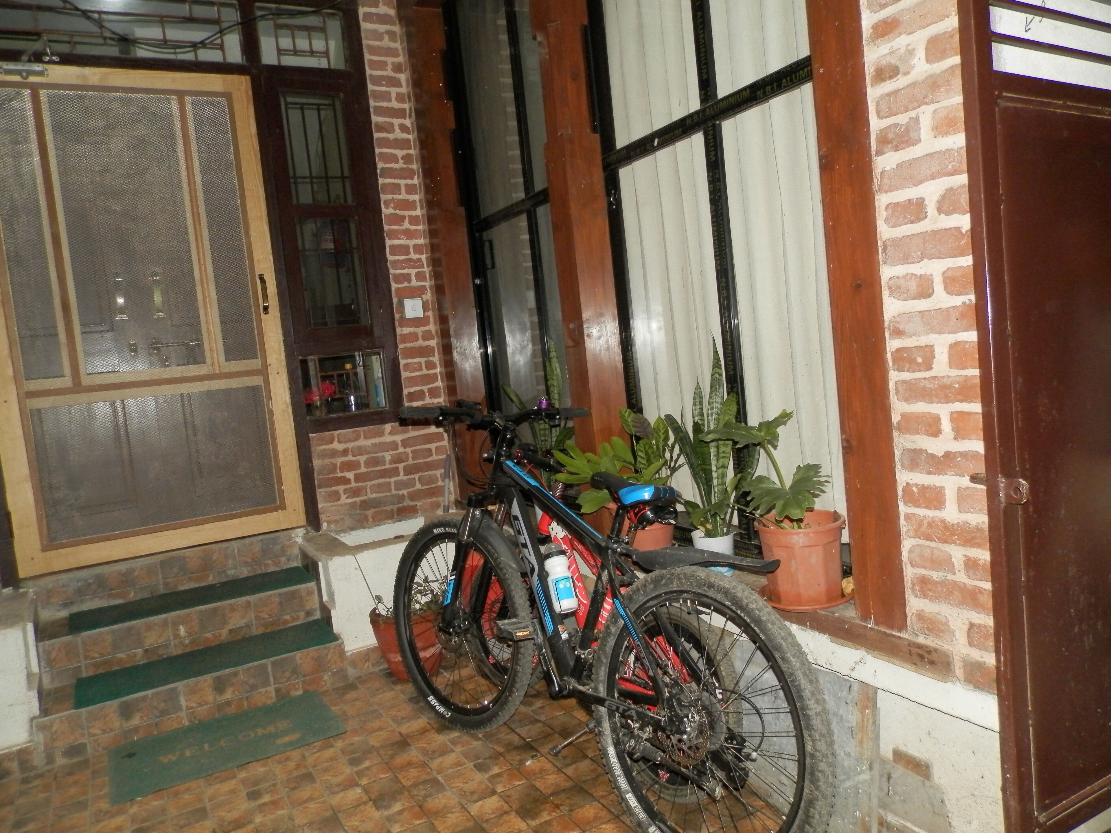 Uma bicicleta estacionada em frente a um edifício de tijolos, com porta e janelas.