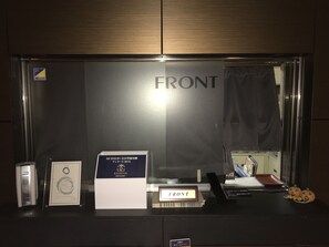 A reception area with a 'FRONT' sign, a 'MEMBERS' box, a framed certificate, a nameplate, and a small pumpkin decoration.