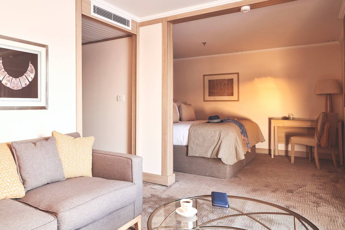 A hotel room with a sofa, a bed, a desk, and a chair.