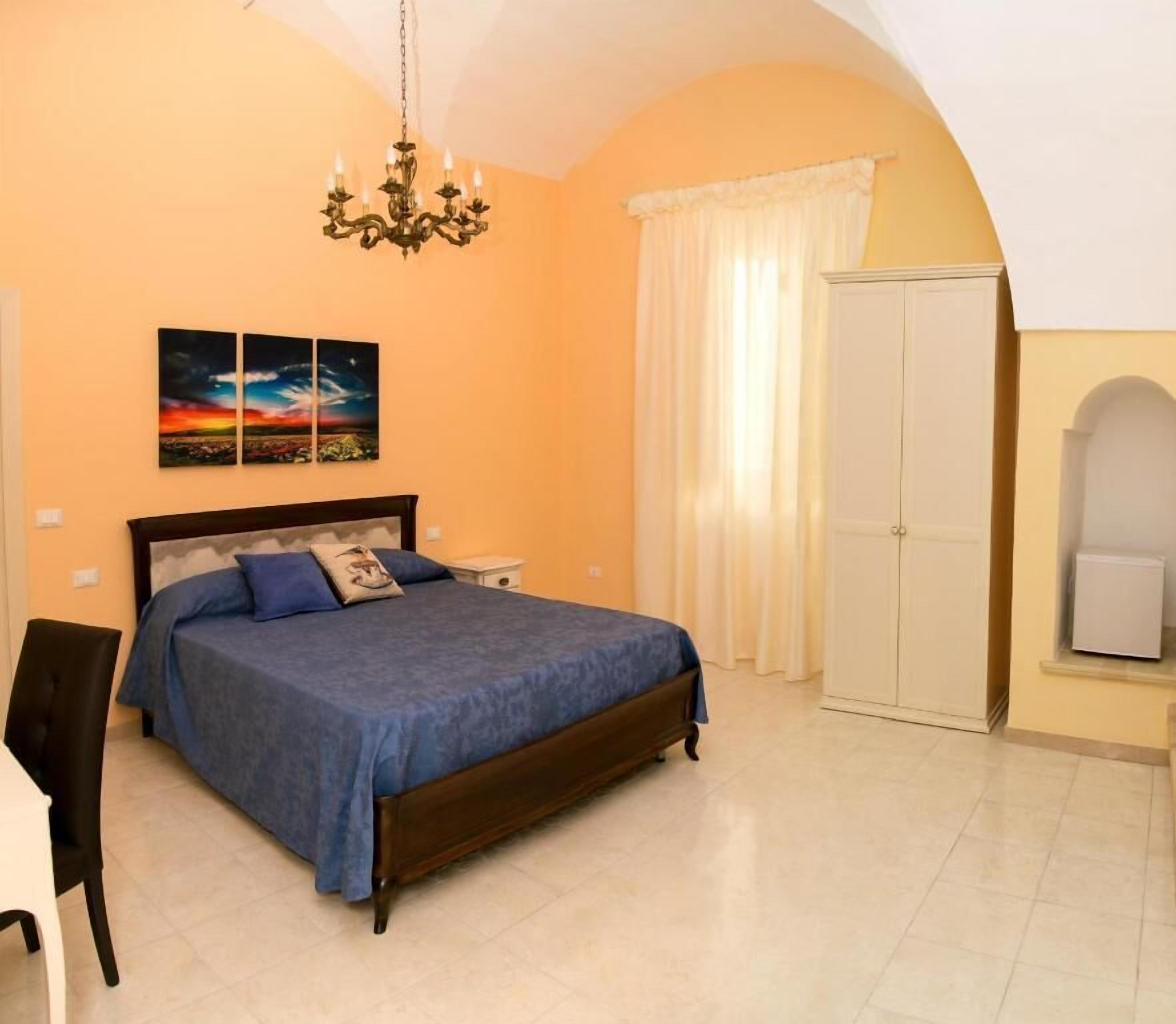 Una camera da letto con un letto, un comodino, una sedia, un armadio e un lampadario.
