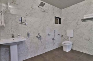 Ein Badezimmer mit Marmorwand, Waschbecken, Toilette und Dusche.