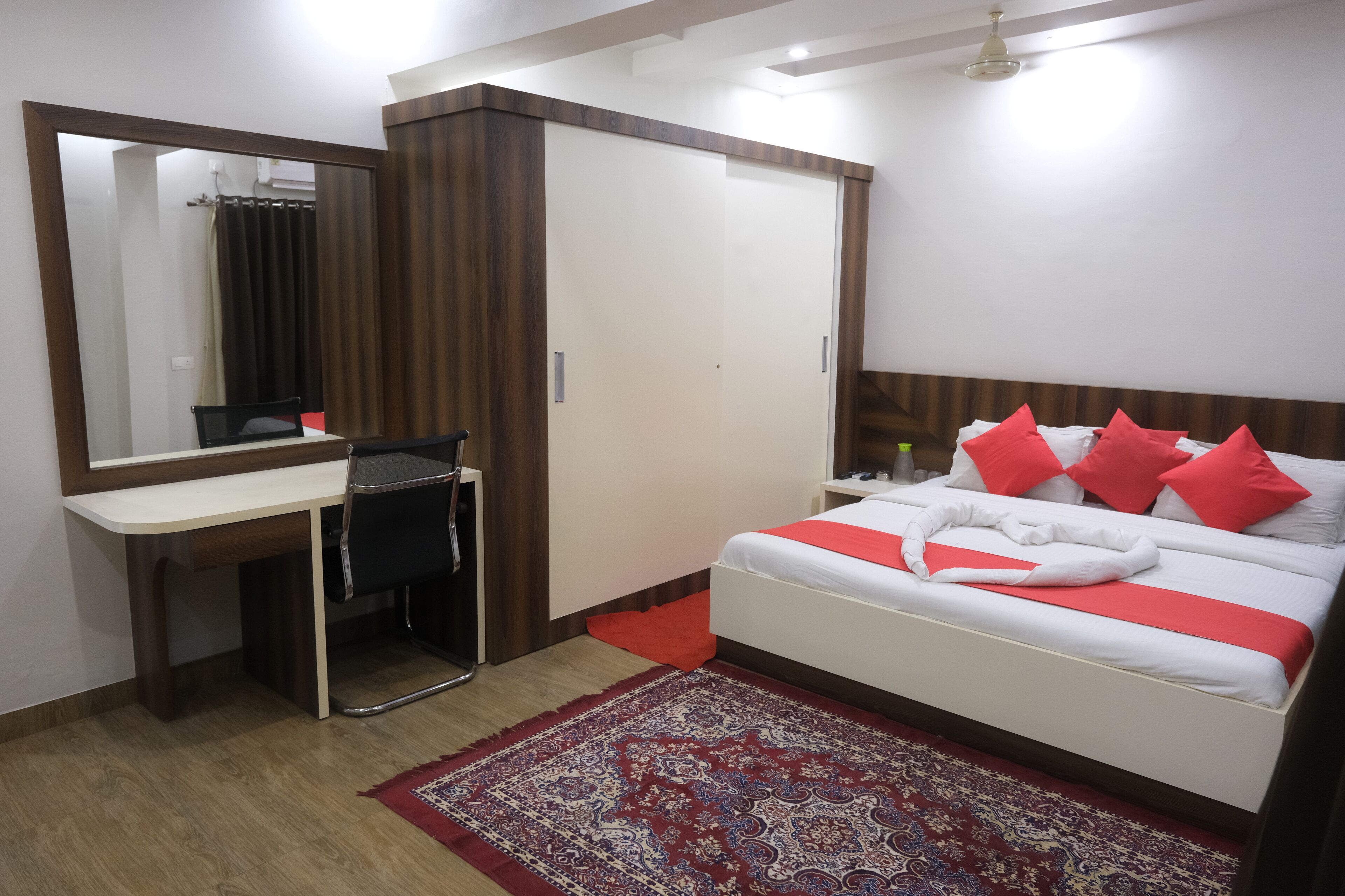 A bedroom with a bed, a desk, a chair, a wardrobe, and a mirror.
