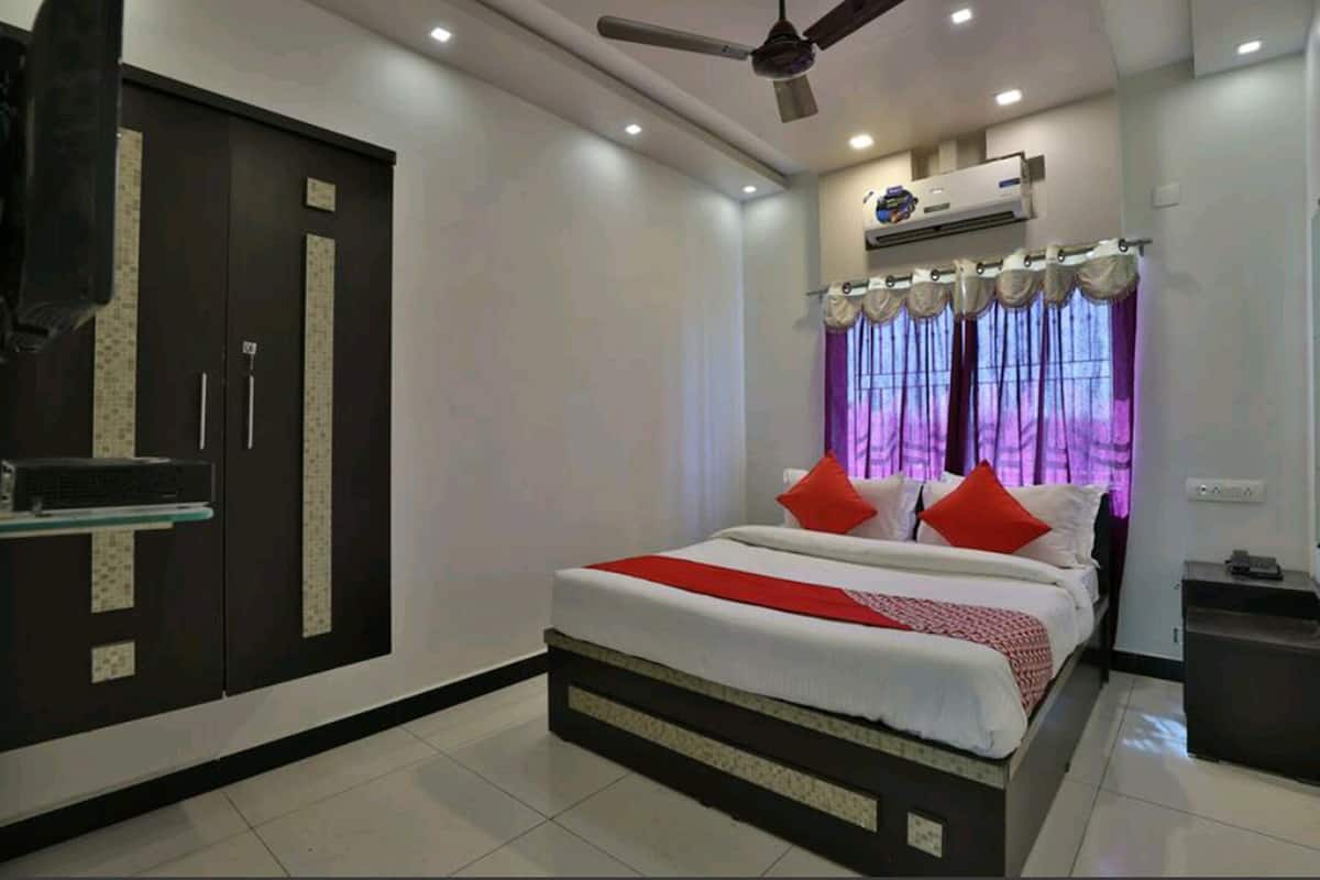 A bedroom with a bed, a wardrobe, an air conditioning unit, and a ceiling fan.