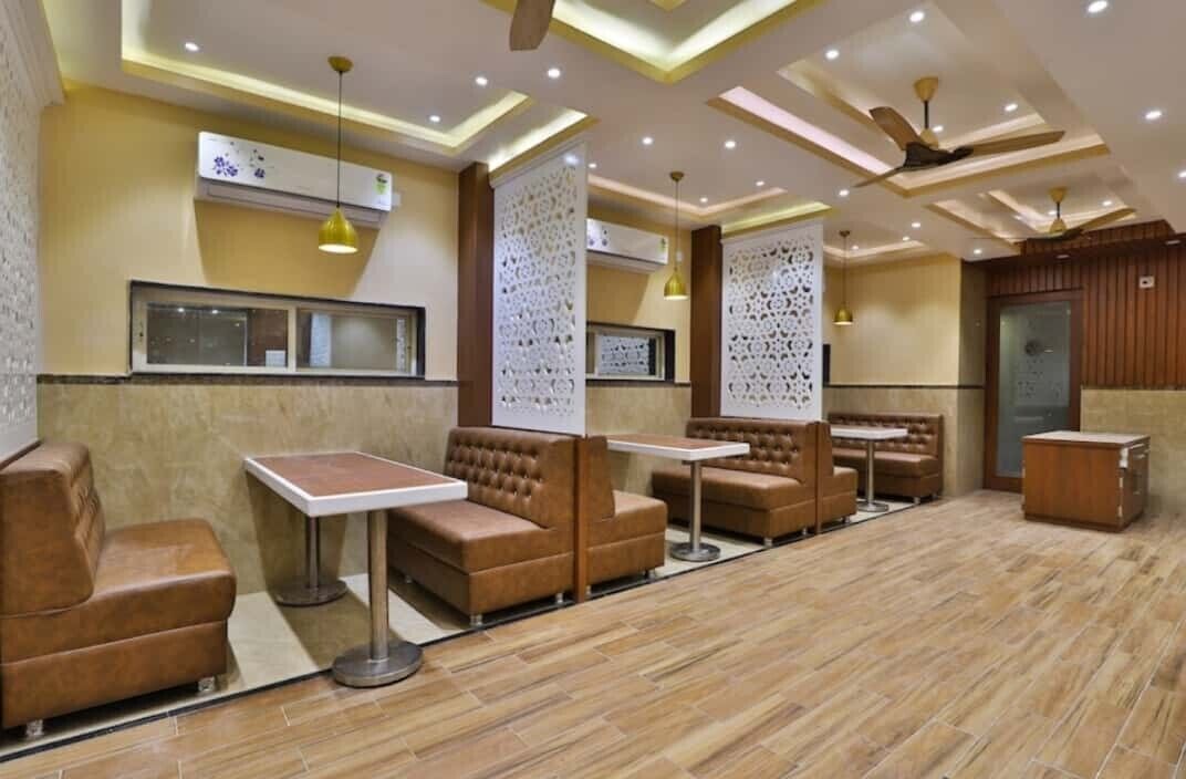 Una moderna area lounge con diverse disposizioni di posti a sedere, tra cui divani e tavolini, e un soffitto con illuminazione a incasso e ventilatori.