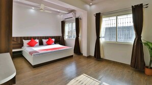 A bedroom with a bed, a ceiling fan, an air conditioning unit, a window with curtains, and a potted plant. - Hotel Centre Point (Mundra)