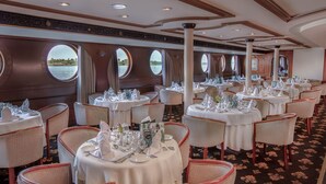 A formal dining area with round tables, white tablecloths, and wicker chairs. - Jaz Celebrity Nile Cruise - Every Saturday from Luxor for 07 and 04 Nights - Every Wednesday From Aswan for 03 Nights (Luxor)