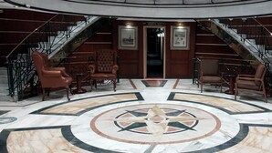 A lobby with a central circular marble design, two staircases, and leather armchairs. - Jaz Celebrity Nile Cruise - Every Saturday from Luxor for 07 and 04 Nights - Every Wednesday From Aswan for 03 Nights (Luxor)