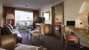 A hotel room with a sofa, a dining table, a TV, a laptop, and a desk with a chair. - JAZ Crown Emperor Nile Cruise - Every Thursday from Luxor for 07 & 04 Nights - Every Monday from Aswan for 03 Nights (Luxor)