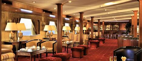 A spacious hotel lobby with multiple seating areas, including sofas and armchairs, arranged around a central coffee table.