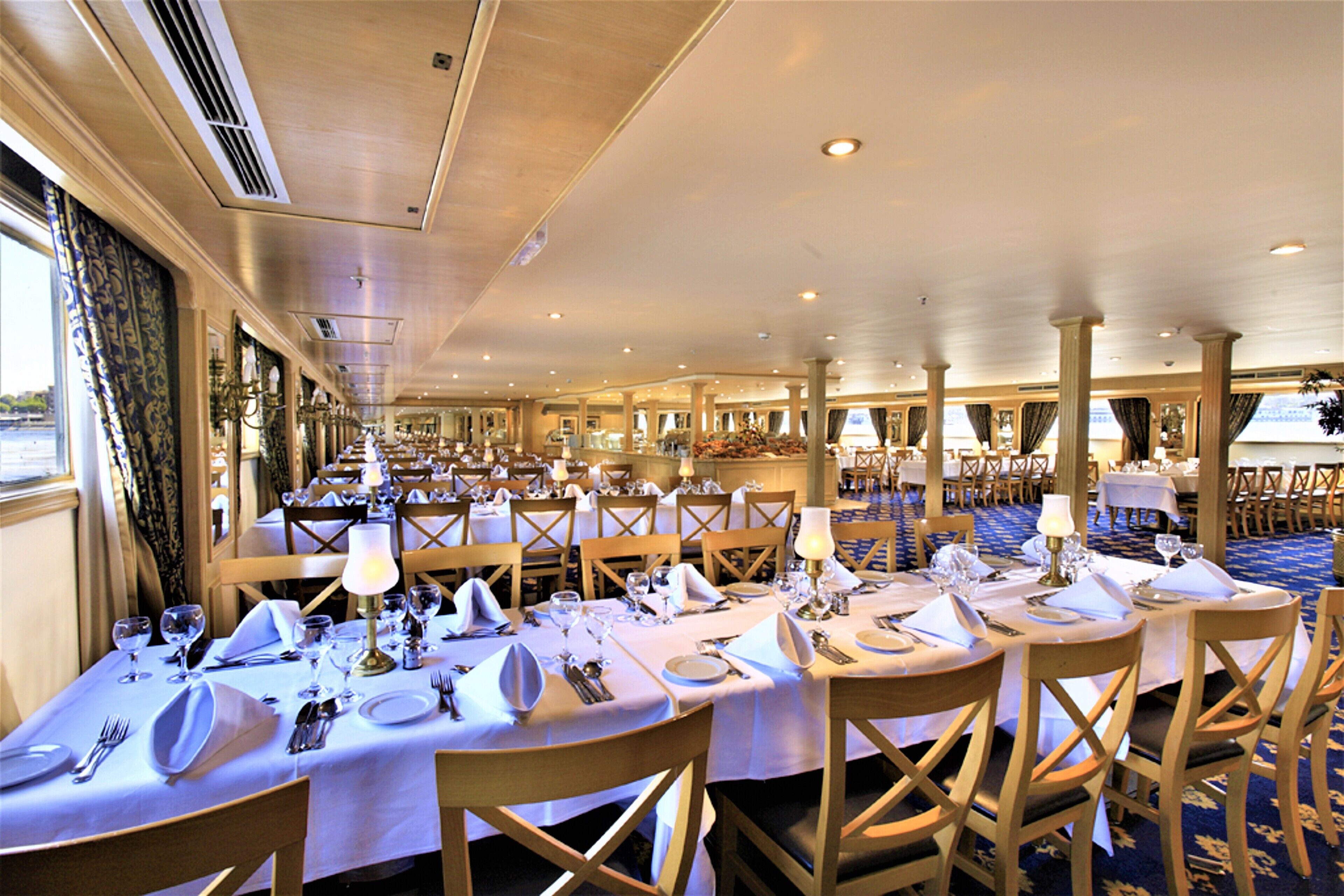 A large banquet hall with multiple tables set for dining, featuring chandeliers and a high ceiling.