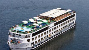 A large, multi-deck river cruise ship with outdoor seating areas and a covered upper deck. - Jaz Crown Prince Nile Cruise - Every Monday from Luxor for 07 & 04 Nights - Every Friday From Aswan for 03 Nights (Luxor)