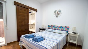 Ein Schlafzimmer mit einem Bett, einem Nachttisch, einem herzförmigen Fotorahmen und einer Holztür.