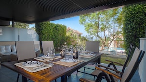 An outdoor dining area with a wooden table set for four, surrounded by chairs.