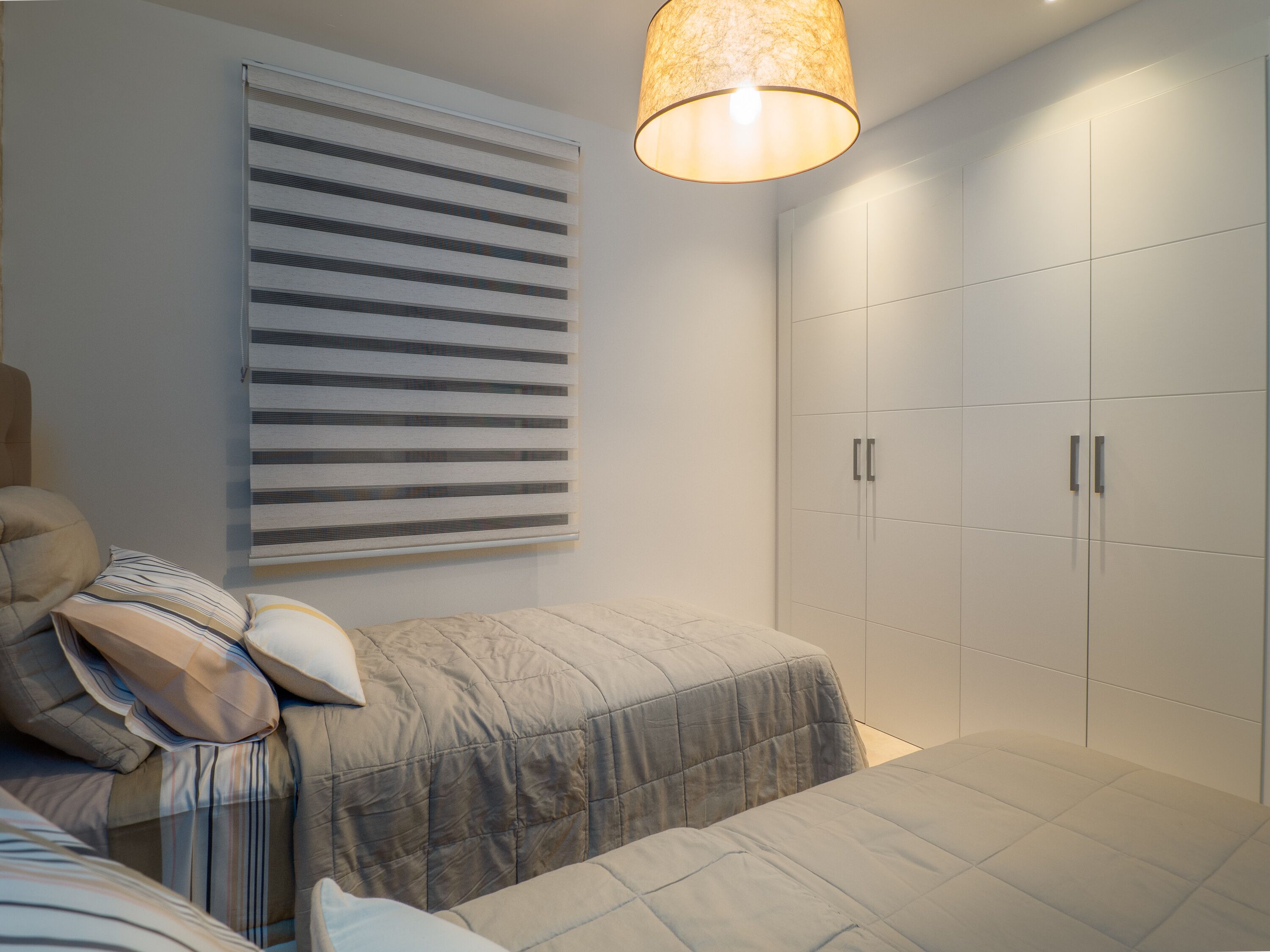 Un dormitorio con cama, mesita de noche, lámpara y armario.