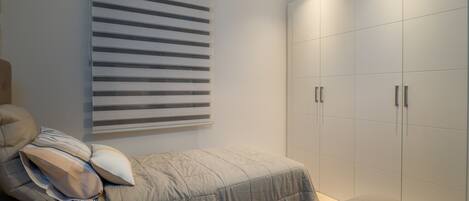 Un dormitorio con cama, mesita de noche, lámpara y armario.
