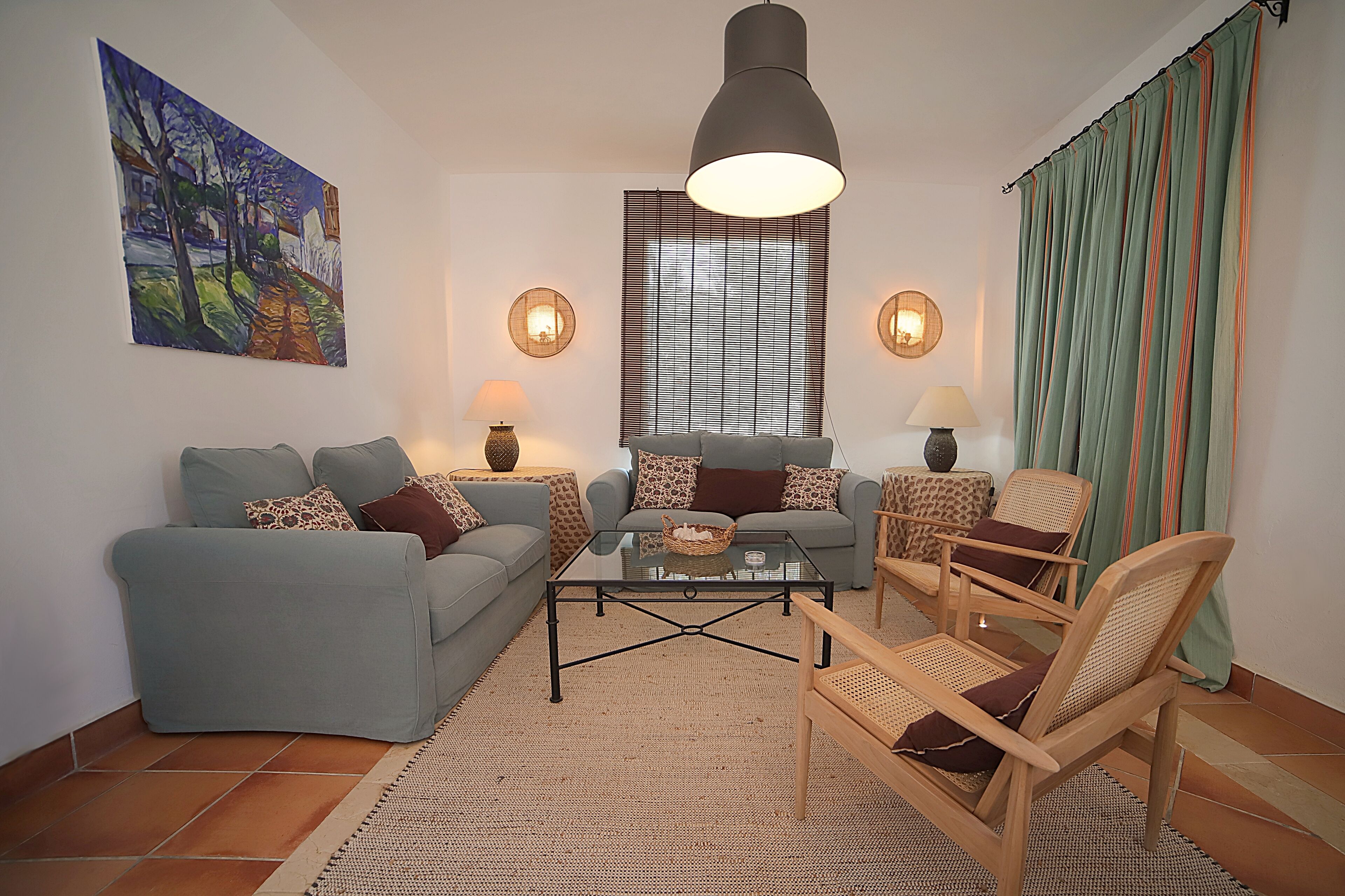 A living room with a sofa, armchairs, a coffee table, and a painting on the wall.