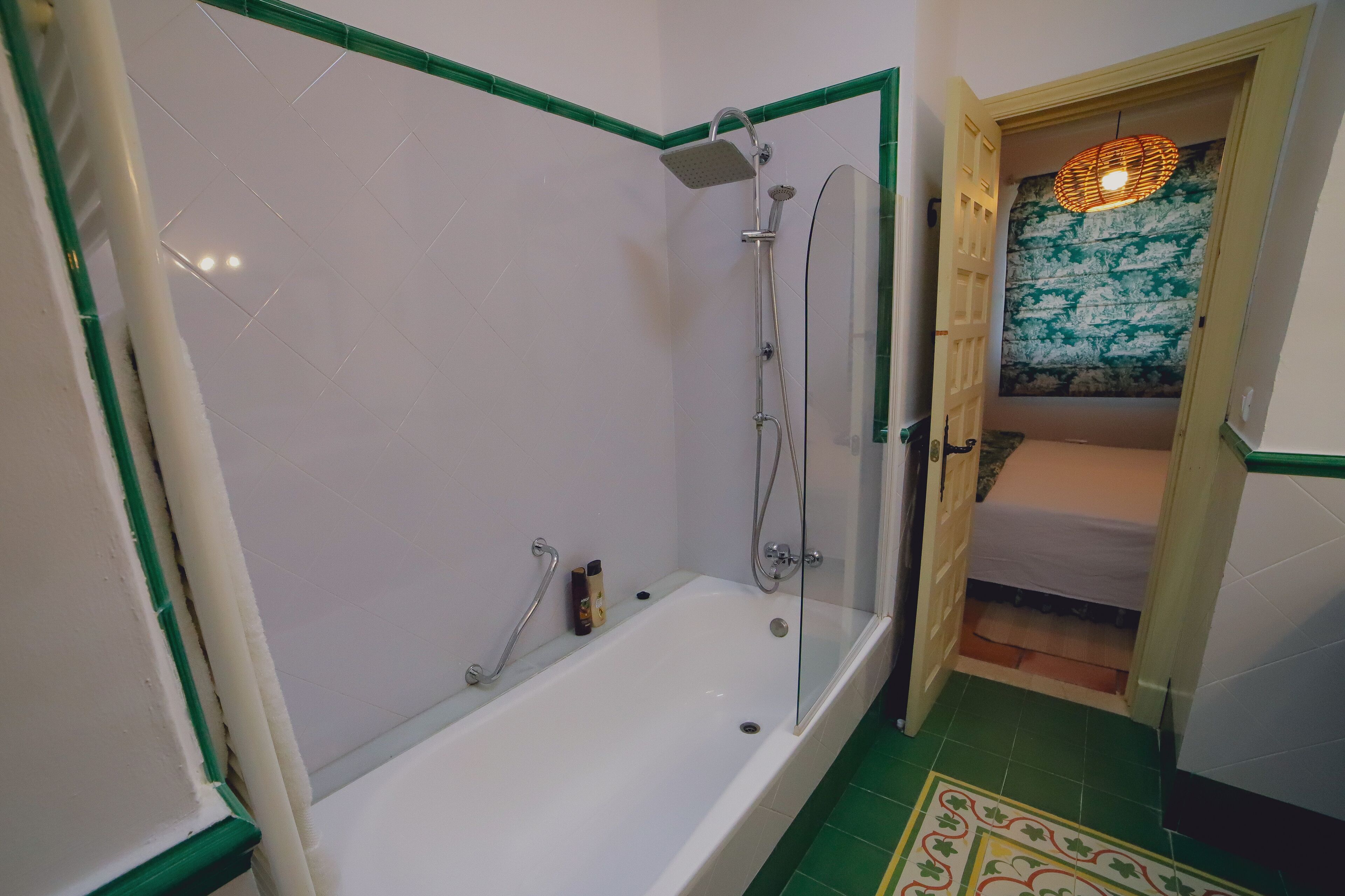 Un baño con bañera, ducha y una cama pequeña.