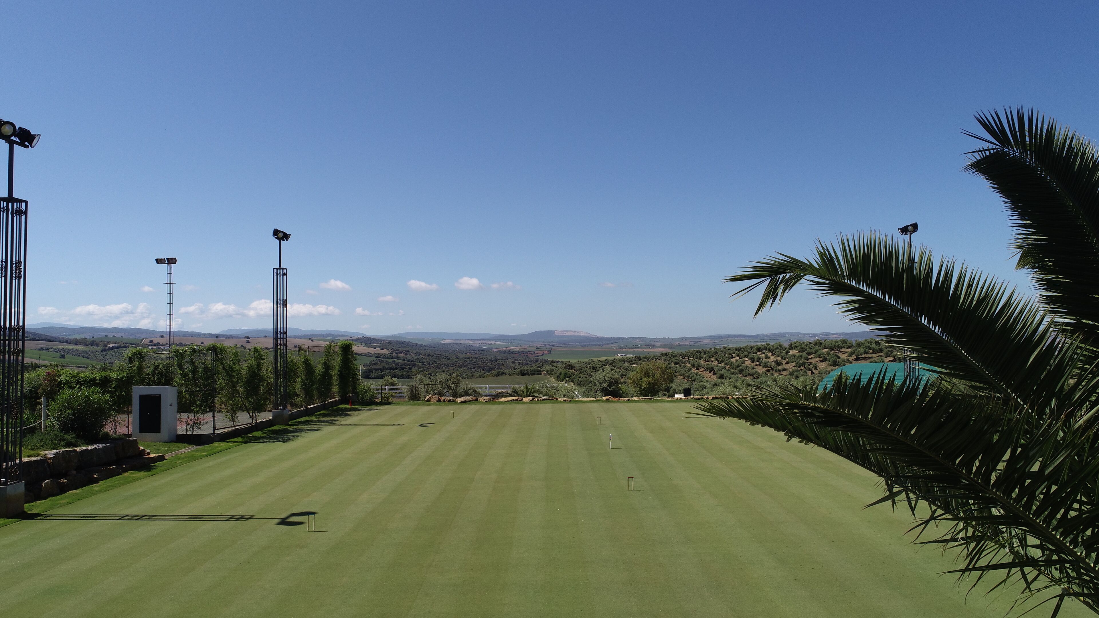A golf course with a clear view of the surrounding landscape, including distant hills and a body of water.