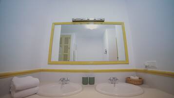 A bathroom with two sinks, a mirror, and a yellow-framed mirror.