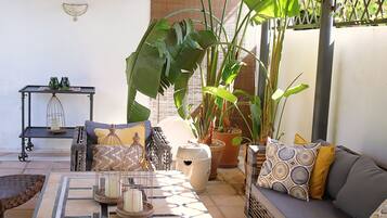 A cozy patio area with a sofa, a small table, and various potted plants.