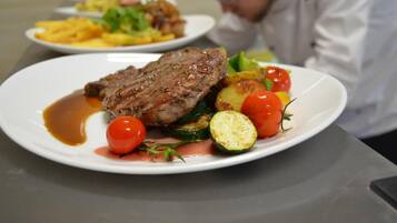 Una mesa con platos de comida, incluyendo filete y verduras.