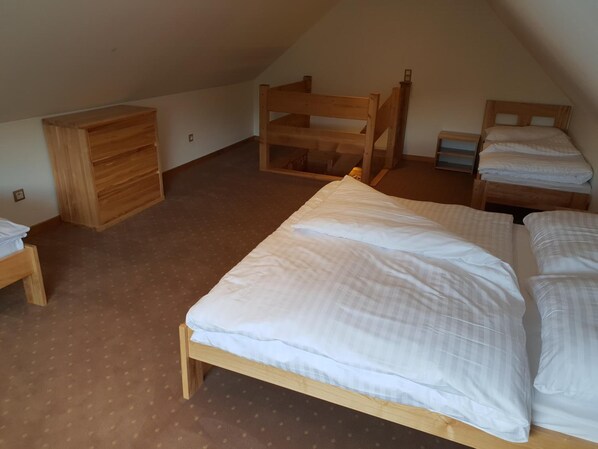 A small, cozy room with a single bed, a wooden dresser, and a bunk bed.