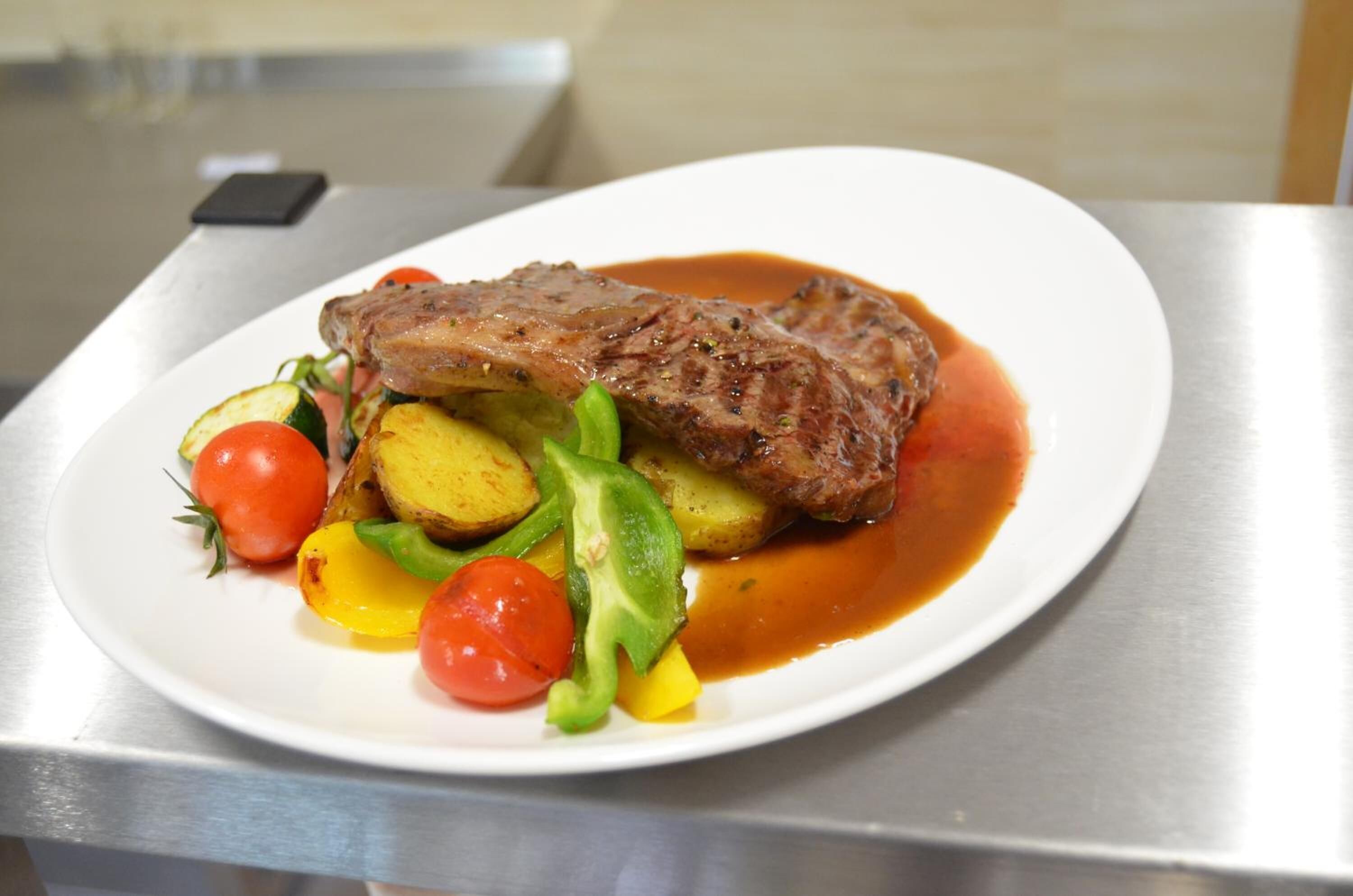 A plate with a steak, vegetables, and sauce.