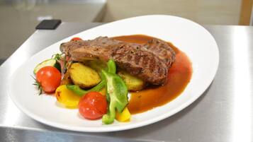 Un plato con un bistec, verduras y salsa.
