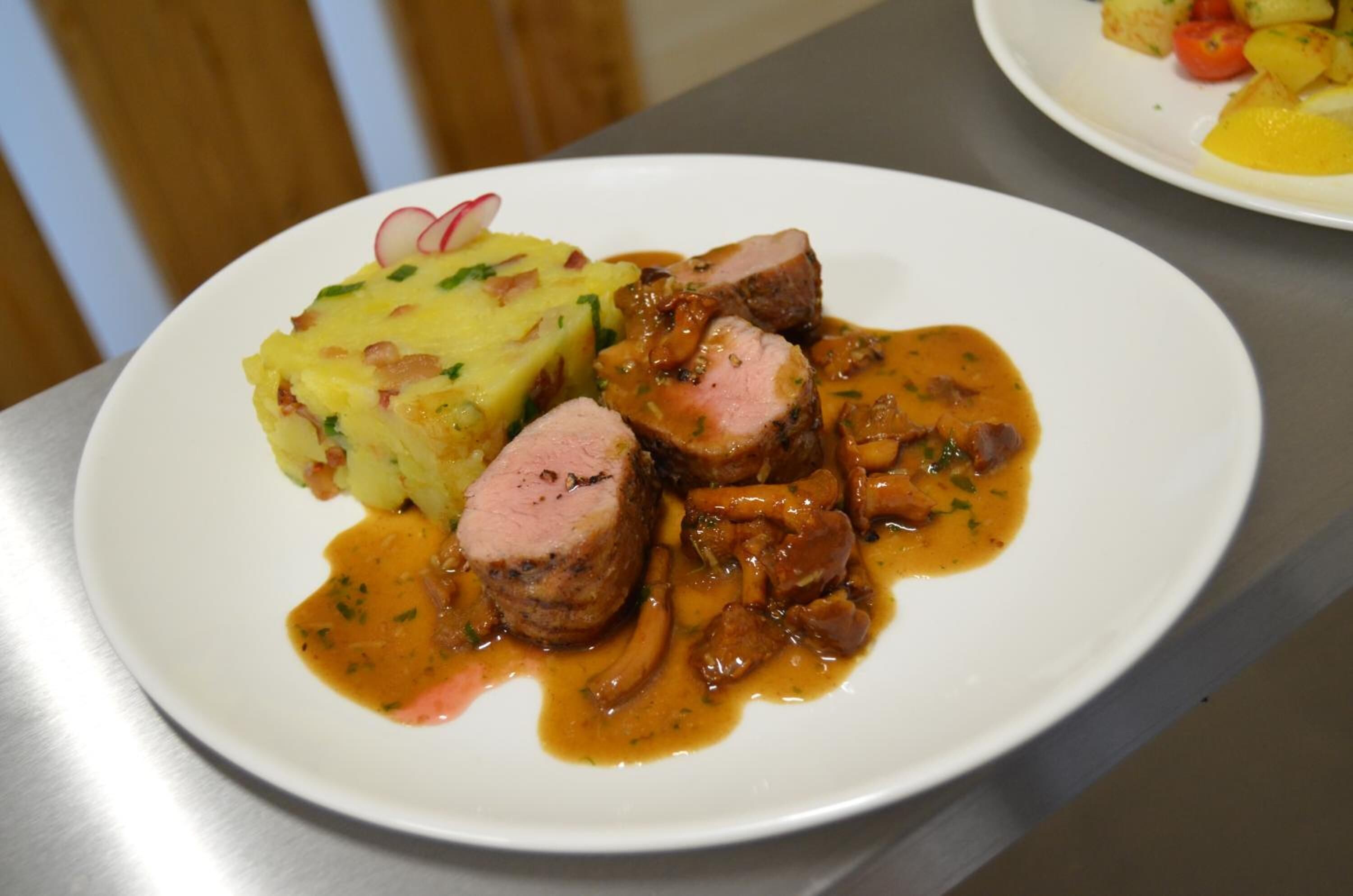 En tallerken med skiver af kød, kartoffelmos og svampesauce.