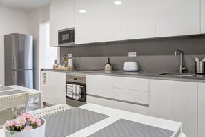A modern kitchen with stainless steel appliances, a microwave, and a kettle.