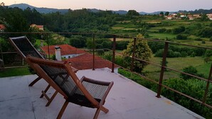 Terraço com duas cadeiras de descanso com vista para uma paisagem pitoresca com casas e vegetação.