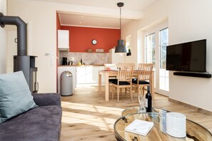 A modern living room with a sofa, a glass coffee table, and a TV mounted on the wall.