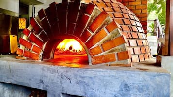 Un horno de ladrillo con fuego ardiendo en su interior, sobre una base de concreto.