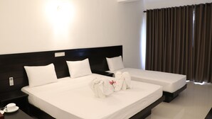 A hotel room with two beds, a nightstand with a phone, and a window with curtains. - Rest House Tangalle (Tangalle)