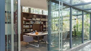 A modern library with glass walls, a wooden bookshelf, and a table with chairs. - Leliving Butterfly Resort Lijiang (Lijiang)