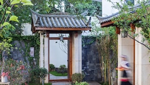 A traditional Chinese gate with a tiled roof, leading to a stone pathway surrounded by greenery. - Leliving Butterfly Resort Lijiang (Lijiang)