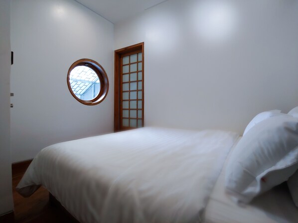 A bedroom with a bed, a window, and a door. - Binh Minh Ecolodge (Cai Von)