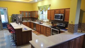 Una cocina con armarios de madera, un refrigerador de acero inoxidable, un microondas y una estufa.