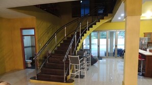 Un hall espacioso con una escalera central, una recepción y vistas al exterior a través de grandes puertas de cristal.